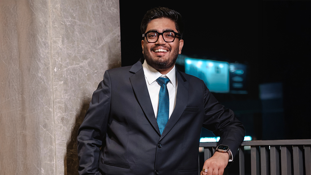 Indra, an international student from India studying Integrated Information Technology at the University of South Carolina, wears a business suit and smiles for the camera.