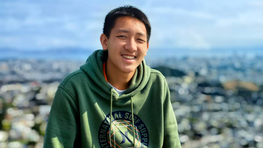 Li, an international student from China, sits overlooking the San Francisco Bay and smiles for the camera.