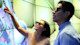 Two UIC international students wear sunglasses and stand by a wall with lit panels during an internship