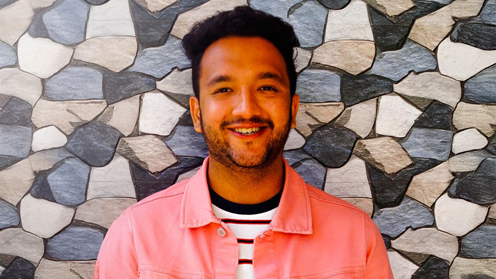 Rahul from India, a former Cleveland State Global student ambassador who earned his master's in computer science from Cleveland State University, stands in front of a stone wall and smiles for the camera.