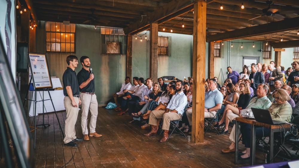 Two international students at LSU stand in front of a seated audience to make a presentation about their startup idea