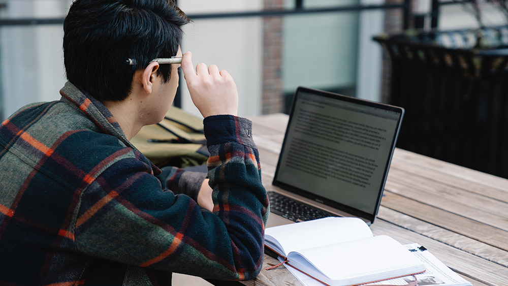 An international student writing up their personal statement on their laptop.
