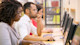 Three international students sit in a row at a table of workstations in the library at their accredited US university.