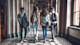 A few from behind four students as they walk down a marble hallway, discussing private universities vs public universities in USA as they prepare to apply to university. 