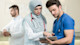 A young female doctor wearing a hijab confers with a young male doctor in scrubs.