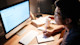 An Asian male international student sits at his desk in front of a monitor and crams for an exam to be held the next day at his US university course.