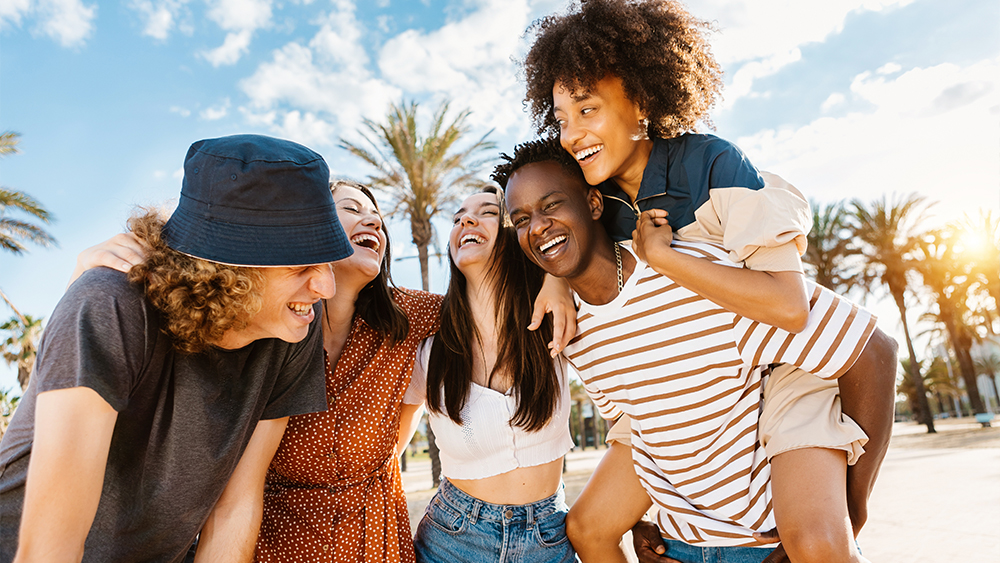 A group of international students attending Shorelight's summer program at FIU hang out under palm trees near the Miami campus.