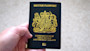 A hand holds a British passport for the United Kingdom of Great Britain and Northern Ireland