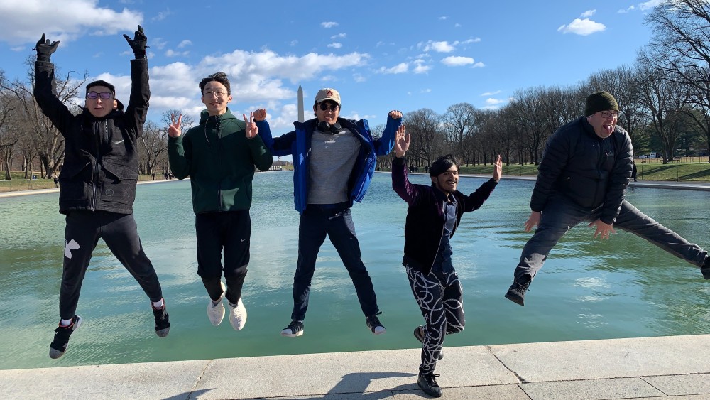 Four Auburn students jump in celebration on the Washington Mall after completing their service project.