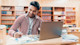 A male international student studies how to write an essay and essay writing while sitting in front of a laptop in a university library.  