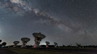 Satellites dishes in a row on the ground in the desert point upward toward a starry sky with a visible Milky Way. International students can earn degrees at aerospace engineering schools in the US. 
