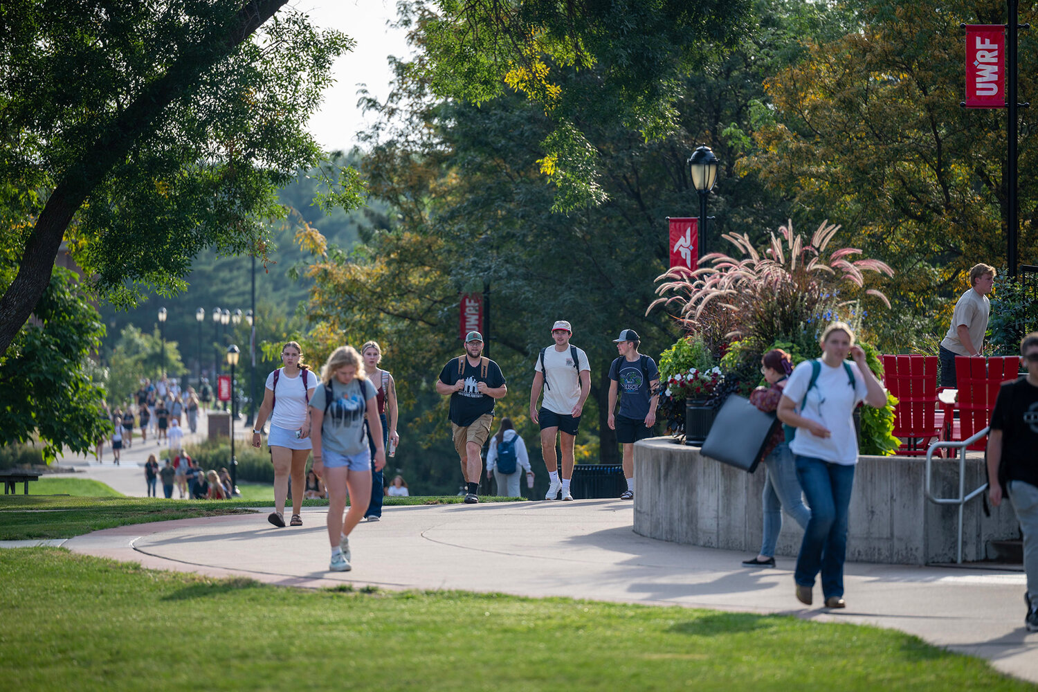 International students walking on the campus garden with UWRF banners in the background.