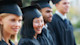 A female international student from Asia wearing a cap and gown stands among fellow graduates on her graduation day at a US university