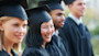 A female international student from Asia wearing a cap and gown stands among fellow graduates on her graduation day at a US university