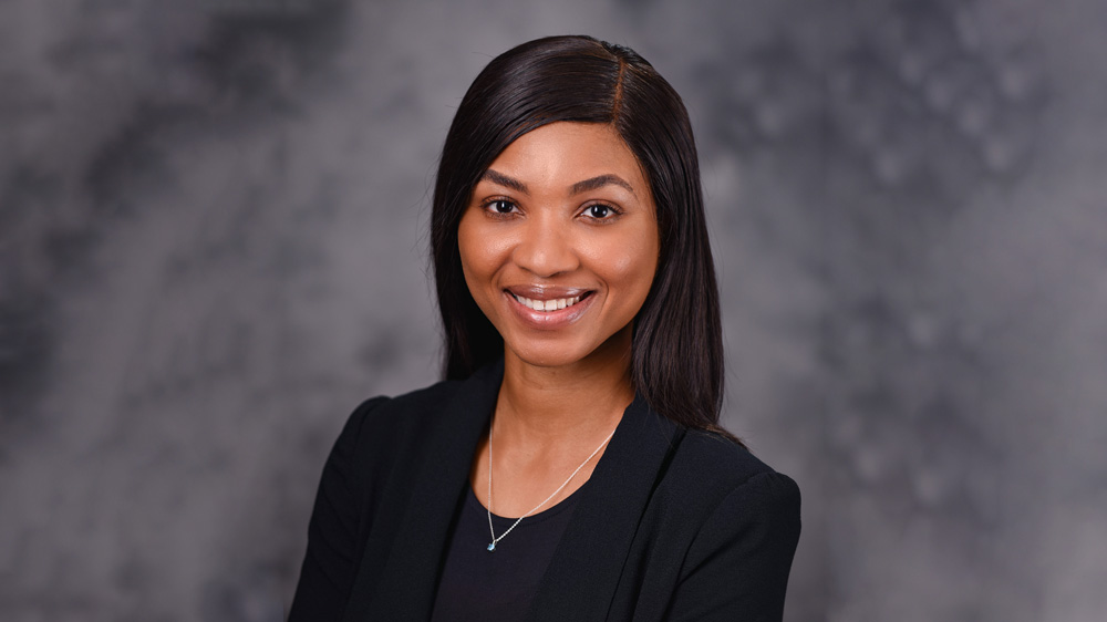Peace, an international student from Nigeria at Auburn University, smiles for the camera against a professional gray backdrop
