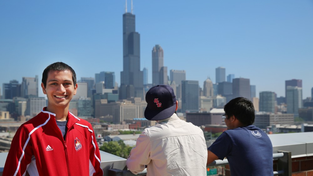 Two University of Illinois - Chicago students on a rooftop with one facing the camera and the other facing the Sears (Willis) Tower in the background.