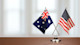 Side by side on a desk are an Australian flag representing Australian universities and the best Australian universities next to a US flag representing options for attending university in the US. 