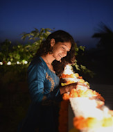 A female South Asian international student stands on a balcony overlooking a ledge filled with lights for Diwali