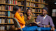 Three international students from Nigeria sit in the library at their US university and discuss their latest assignment.