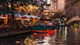 A bottom-lit riverboat passes restaurants with outdoor patios in early evening along the San Antonio River Walk.