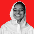 Sakina Taher, a copywriter with Surge Global in Sri Lanka, smiles for the camera against a red background