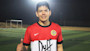 Rodrigo, an international student from Peru at Heriot-Watt University, wears a Duff football jersey and gives a thumbs-up while standing on a football pitch.