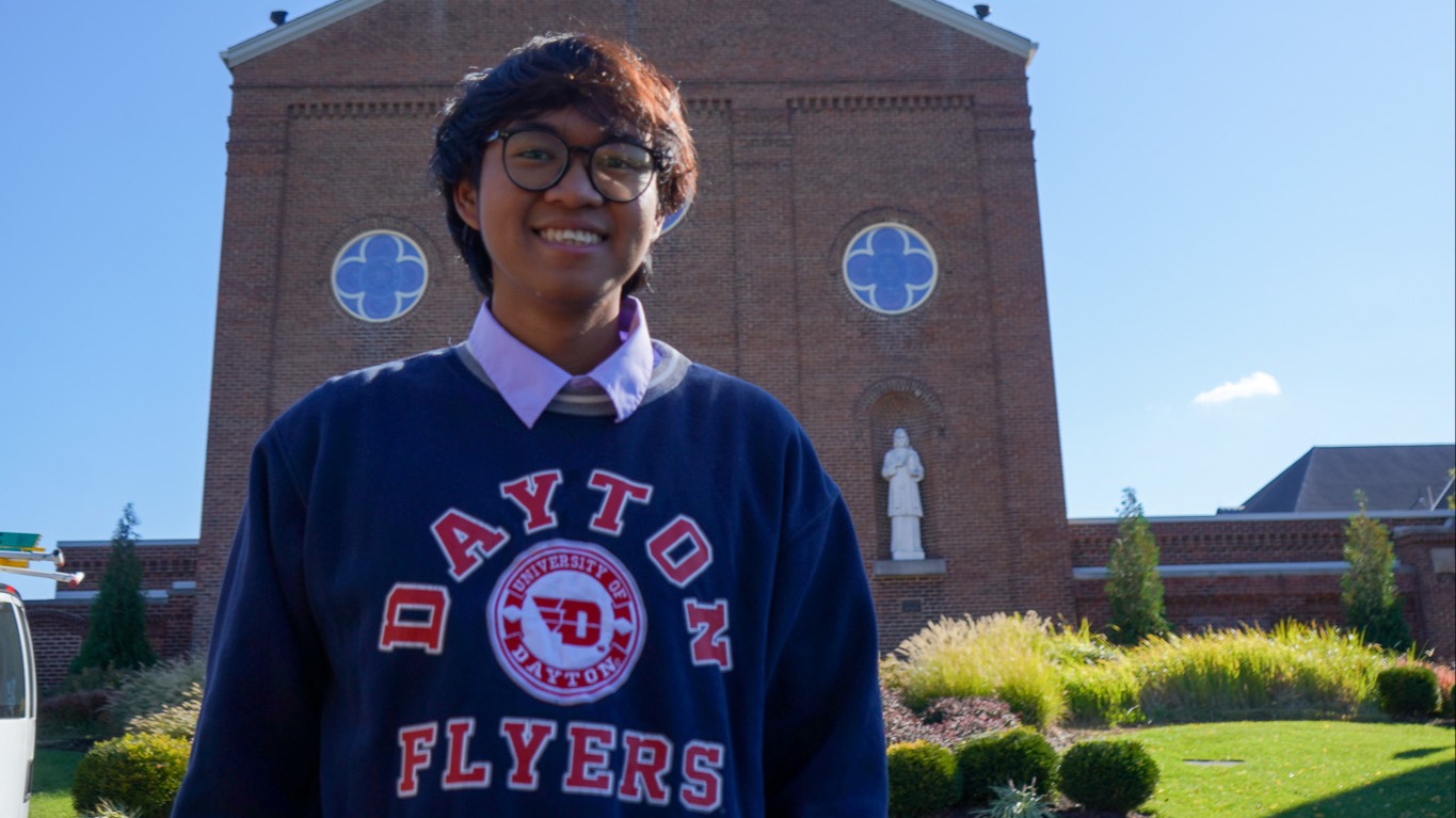 Zay Min, an international student from Myanmar at the University of Dayton, smiles in front of the Chapel of the Immaculate Conception on campus on a sunny fall day.