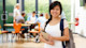A female Filipino student stands in the student center at her US university wearing a backpack and holding a notebook.