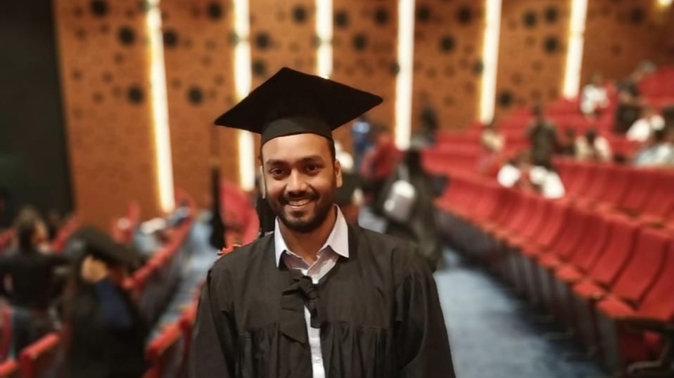 Shrikant, an Indian student at Cleveland State University, wears his cap and gown and walks down an aisle at an auditorium on his graduation day