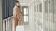 A female international student from Asia walks through an airport hallway pulling a suitcase before her journey to a US university