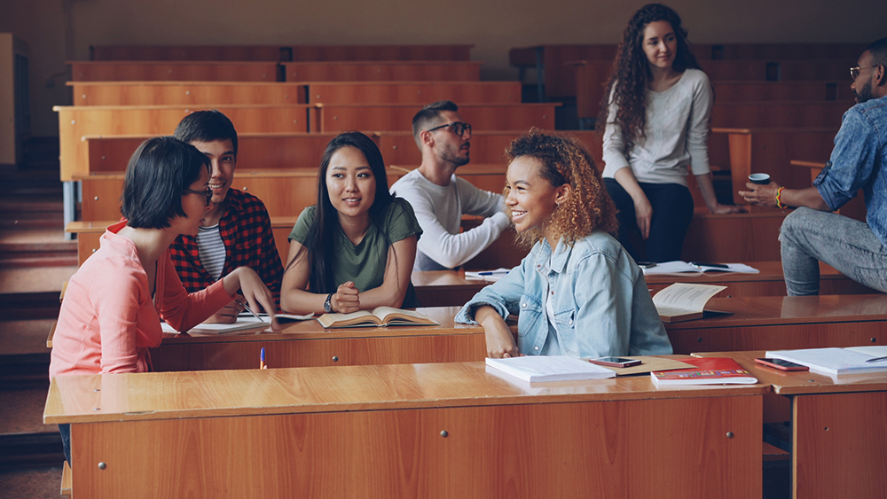 A group of international students sit in a lecture hall at their US university and discuss the new Best Colleges 2026 rankings from U.S. News & World Report. 