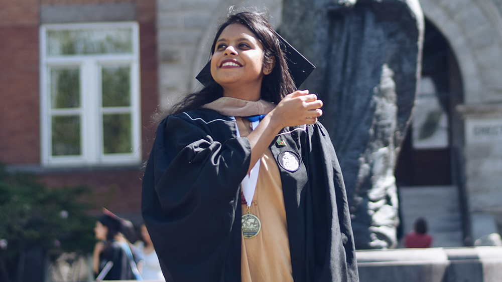 Sarah, an international student from Bangladesh, stands in her cap and gown on graduation day on the Gonzaga University campus.