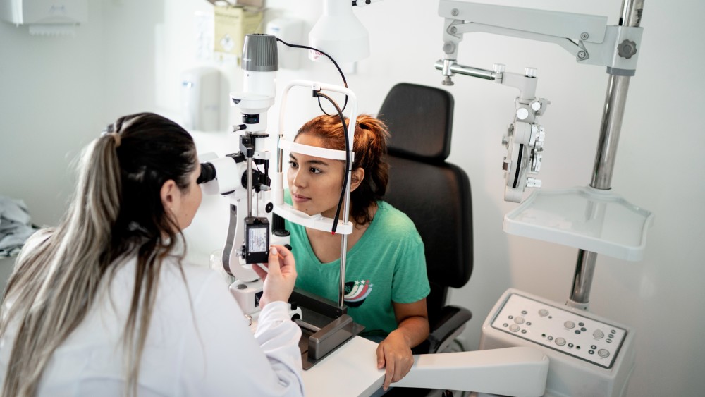 An international student optometrist in training looks through an optometry lens at an optometry patient