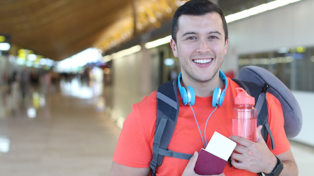A male international student arrives at the airport with his f1 visa and passport