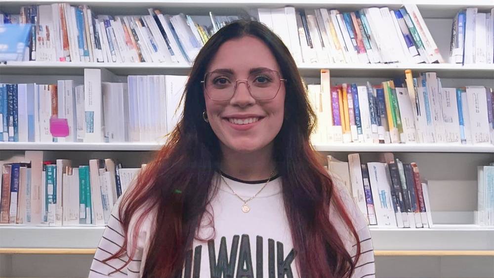 Sarah, an international student from the Czech Republic at Carroll University, stands in front of bookshelves and smiles for the camera.
