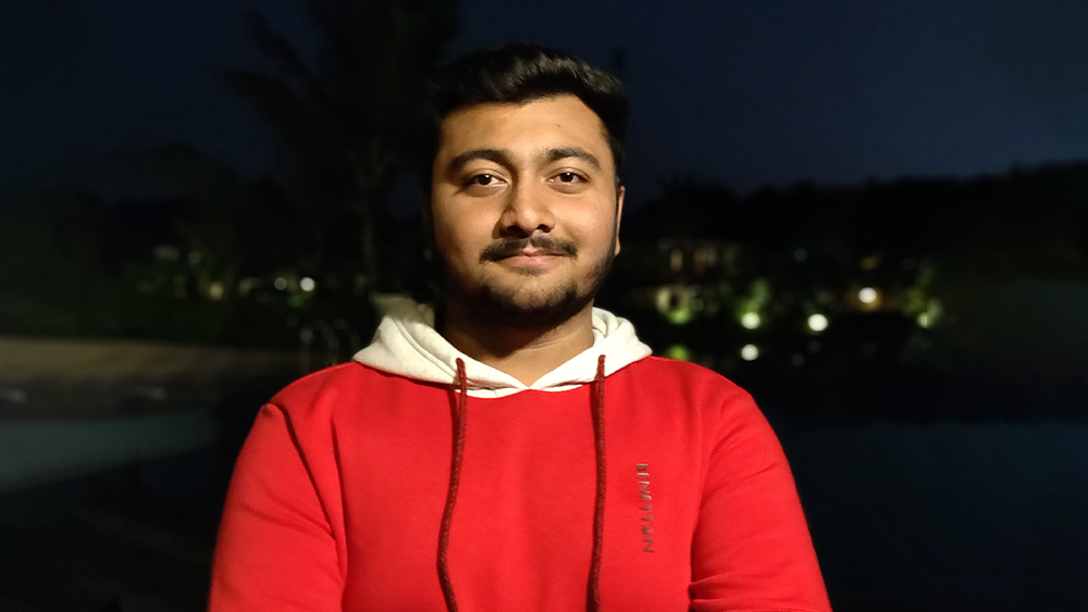 Avadh, an international student from India and student ambassador for UIC Global, wears a red sweatshirt with a white hood and smiles for the camera