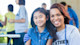 A female college student wearing a "volunteer" t shirt with her arm around a young girl, and both are smiling at the camera.
