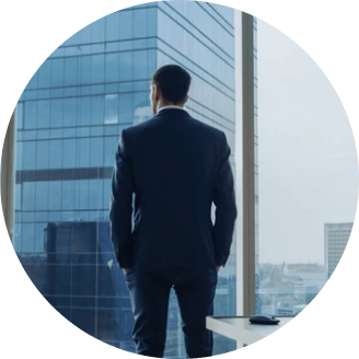Man wearing a suit standing in front of a window looking at a skyscraper