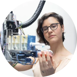 Woman with short wavy hair and glasses working with a device in a manufacturing