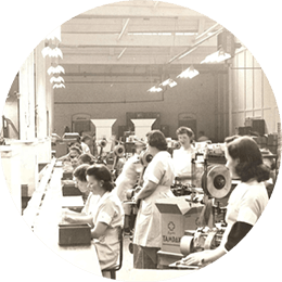 Several white women in uniforms are working in a Tampax factory during world war two. The image is in black and white.