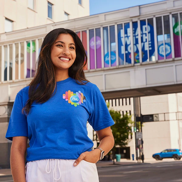 Girl in blue P&G shirt smiling with rainbow bridge in background