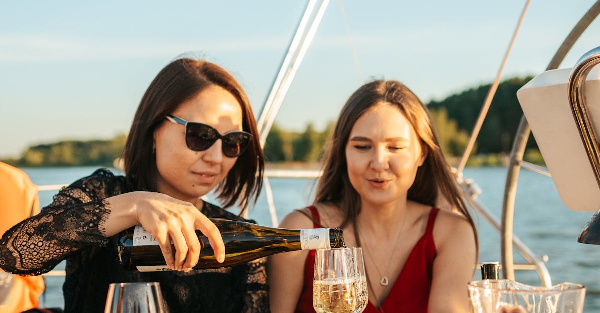 A Woman Wearing Sunglasses Pouring a Drink while Talking to Her Friend