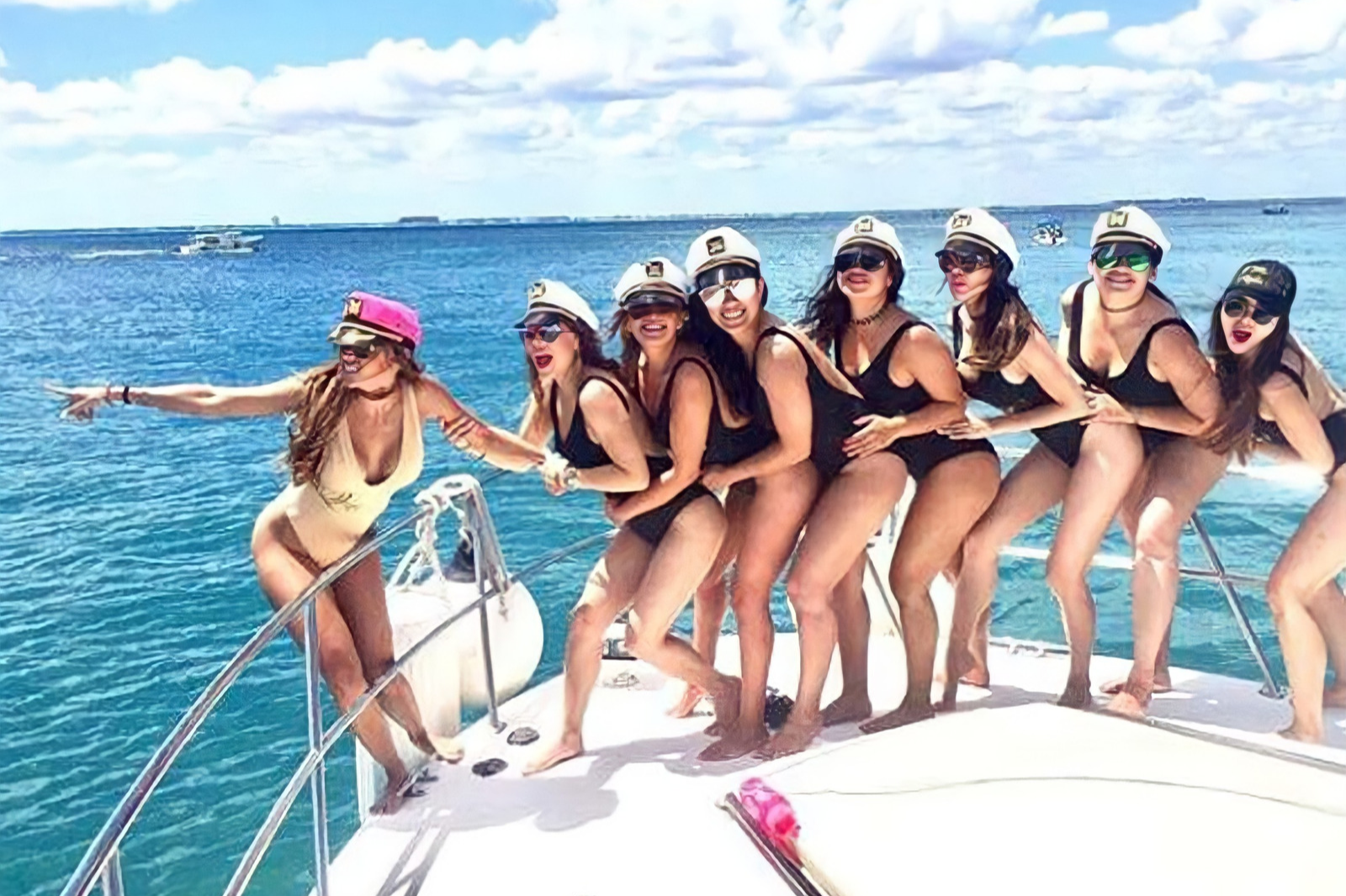 Girls in captain hats posing for a picture on the bow of a boat during a bachelorette party