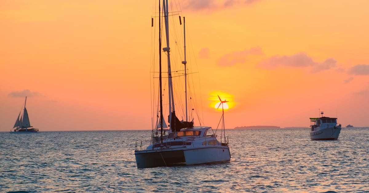 A sailboat is in the ocean at sunset