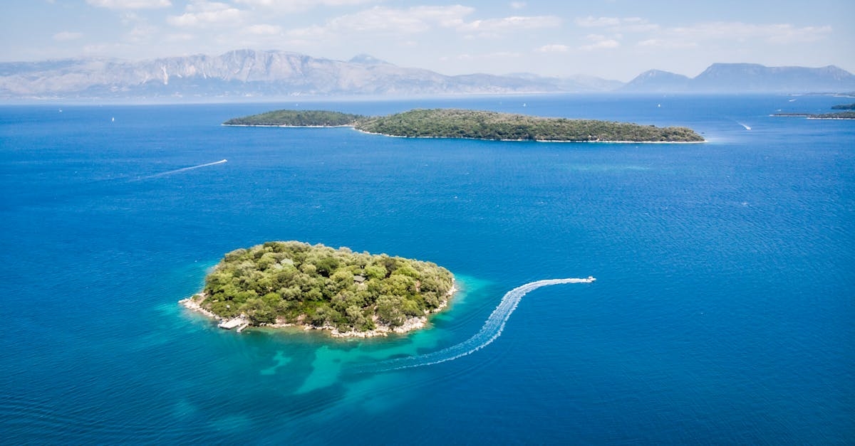 Amazing aerial view of boats floating in turquoise sea near islands with lush green vegetation on sunny day