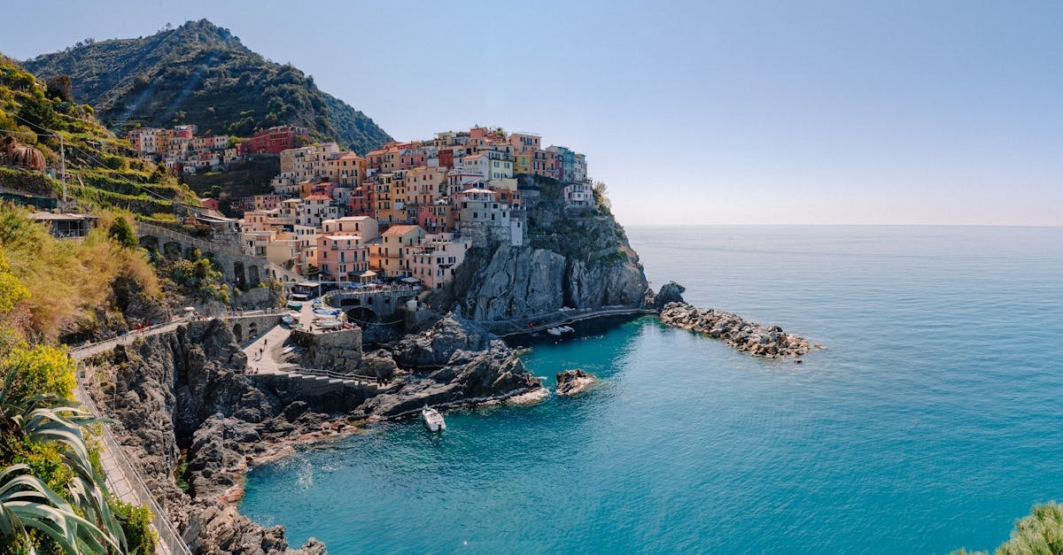 Breathtaking scenery of historic colorful buildings of famous coastal Manarola town located on stony hill in front of turquoise sea on sunny day