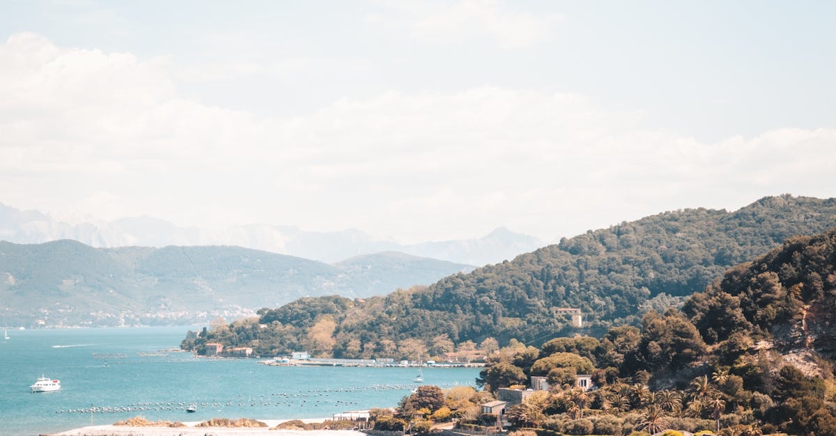 Green and Brown Mountains Beside Blue Sea Under Blue Sky