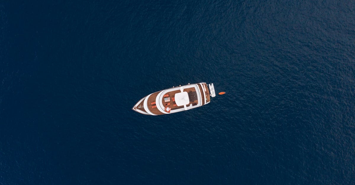 Drone top view contemporary yacht floating on dark blue rippling sea on cam windless day