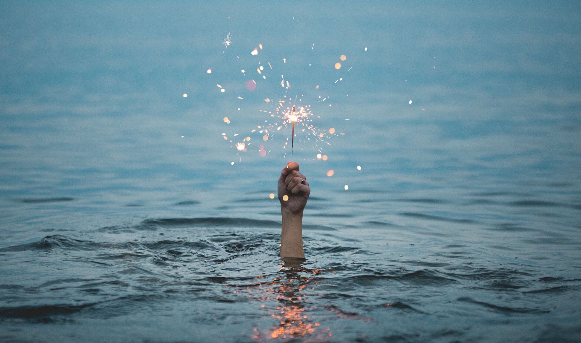 hand holding sparkler out of water