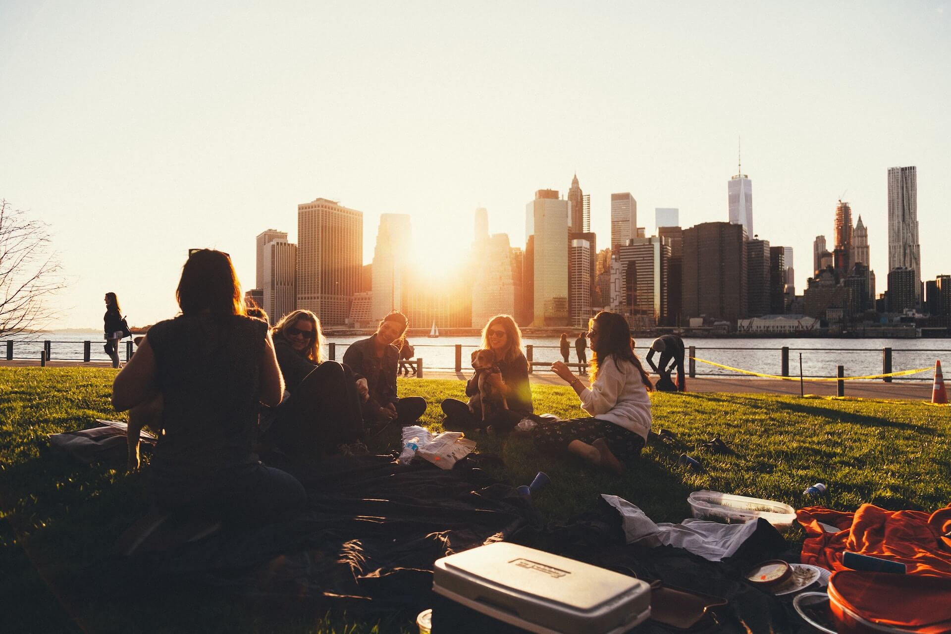 group of friends sitting in park next to water